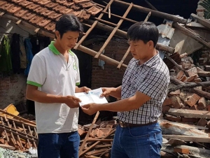 Đại diện Báo Thanh Niên (phải) trao tiền hỗ trợ cho người dân.