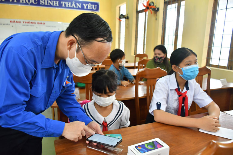 Anh Trần Minh Trí tặng và hướng dẫn em Trần Thị Tố Trinh (lớp 4E Trường tiểu học số 2, xã Xuân Hải, TX Sông Cầu) sử dụng điện thoại để học trực tuyến.